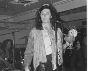 Musician holding a drink on stage performing.