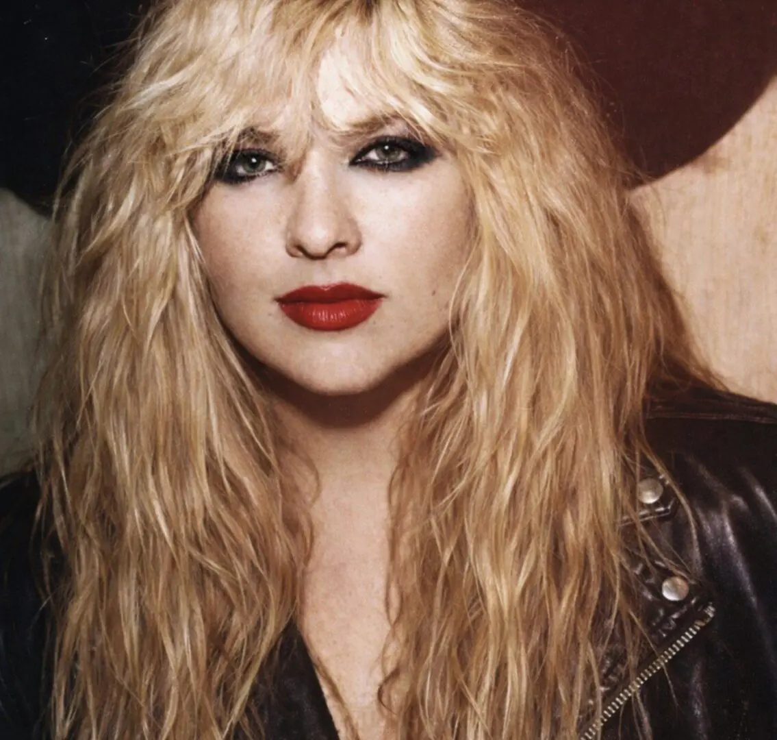 Blonde woman with red lipstick and leather jacket.