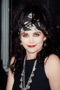 Woman with dark hair and a bandana smiling at the camera.