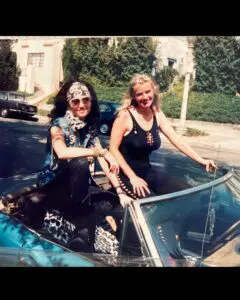 Two women sitting on a convertible car.