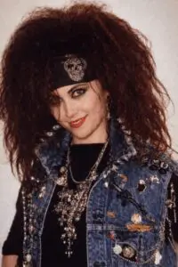 Woman with voluminous curly hair wearing a denim jacket and headband.