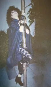 Person in costume climbing a pole outdoors.