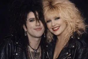 Two people in 1980s rock style with big hair and leather jackets.