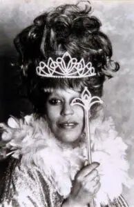 Person with tiara, feather boa, scepter