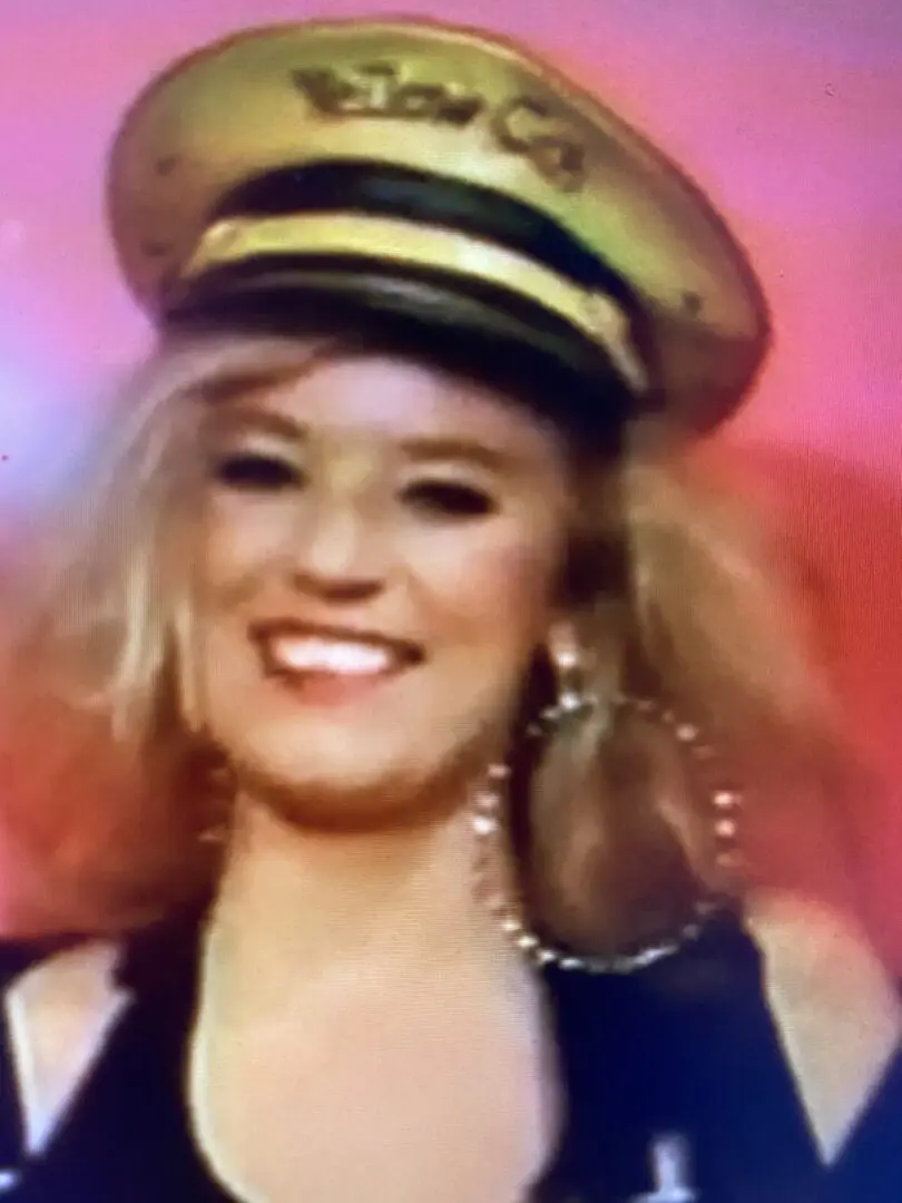 Smiling woman wearing captain's hat and hoop earrings