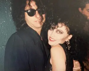 Smiling woman embraced by man in sunglasses