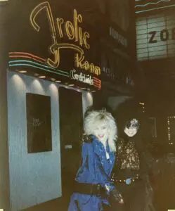 Two people outside neon Frolic Room sign