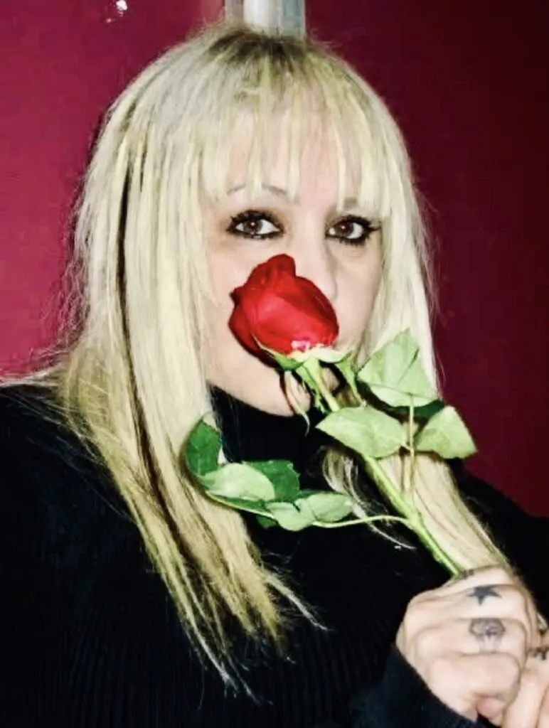 Blonde woman smelling a single red rose